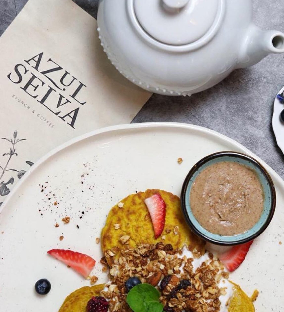 Azul Selva branded napkin, teapot, and breakfast plate
